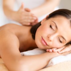 health, beauty, resort and relaxation concept - beautiful woman with closed eyes in spa salon getting massage